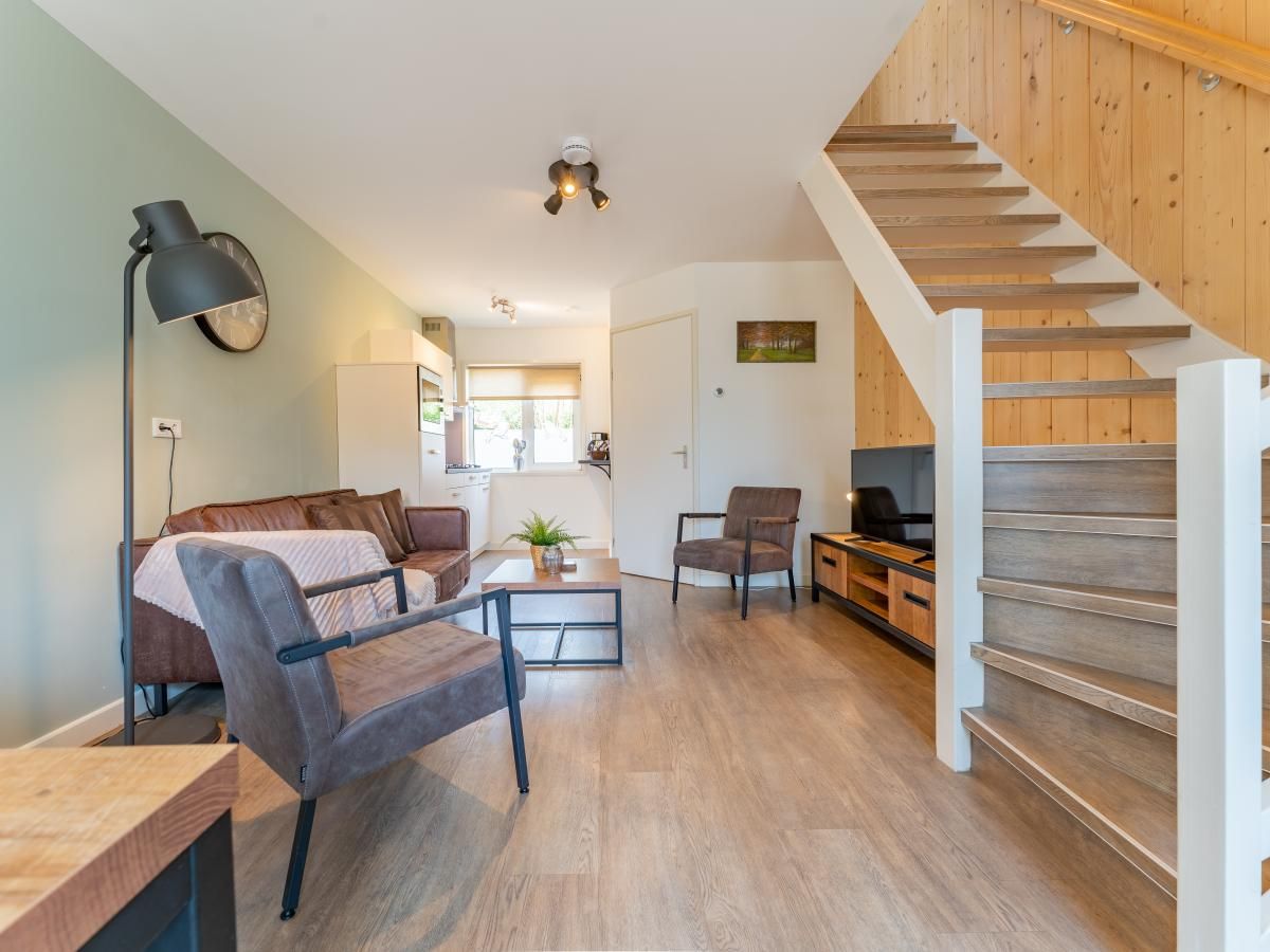 Offenes Wohnzimmer des Ferienhauses Pimpelmees in Hulshorst, Veluwe mit Treppe zum Obergeschoss.