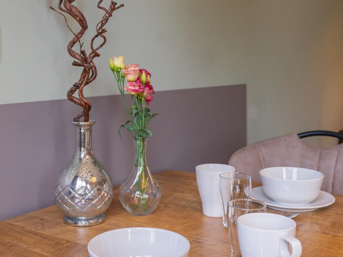 Detail des Esstisches im Ferienhaus Pimpelmees in Hulshorst, Veluwe mit Blumen und Geschirr.