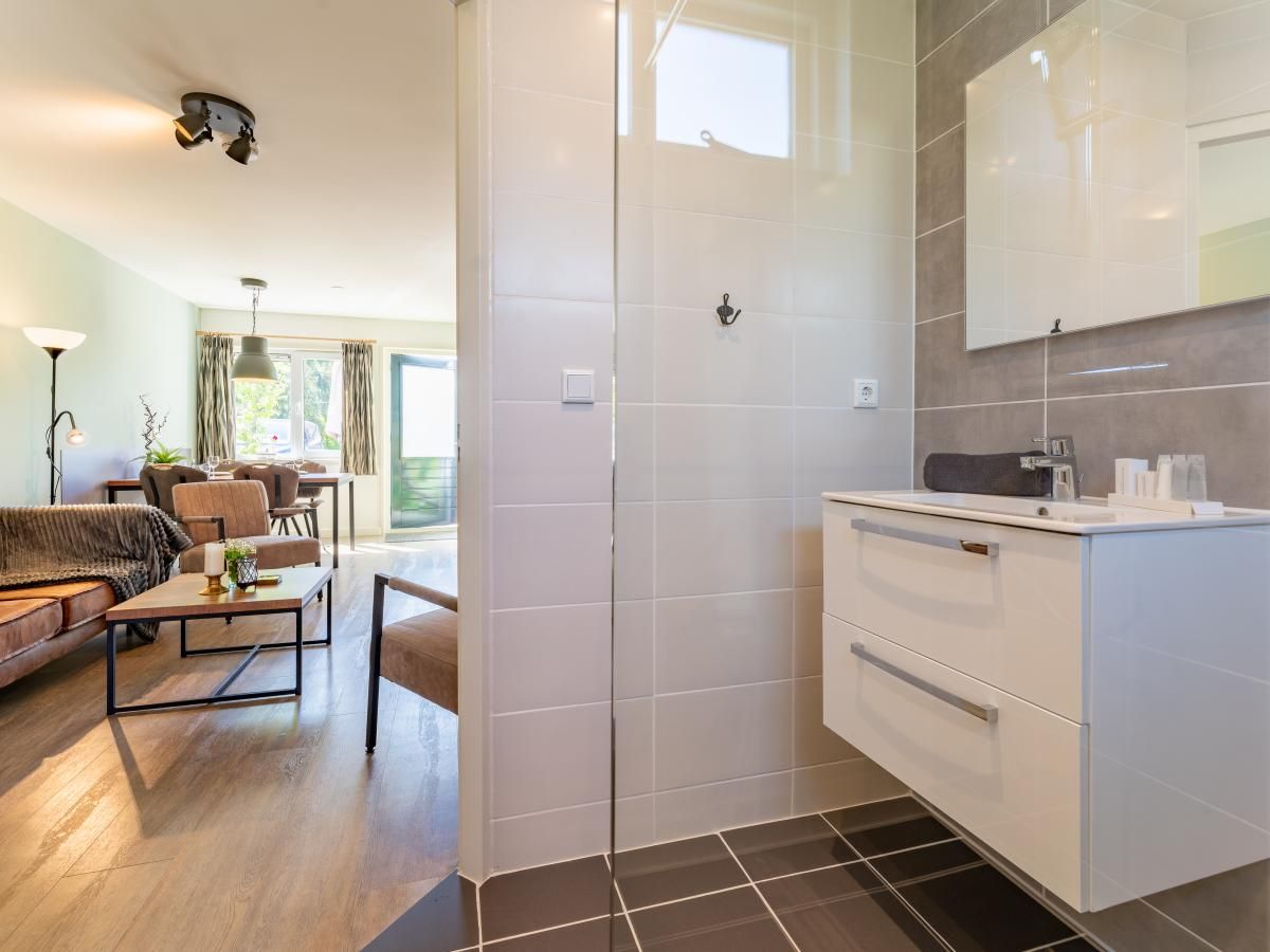 Modernes Badezimmer im Ferienhaus Pimpelmees in Hulshorst, Veluwe, mit begehbarer Dusche und Waschbecken.