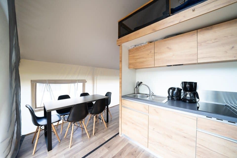 Stilvolle Einrichtung des Glampingtent 6 in Otterlo, Veluwe mit moderner Kueche und Essbereich fuer ein luxurioeses Glamping-Erlebnis.