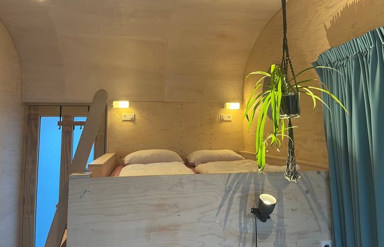 Gezellige slaapkamer in Vakantiehuis in Otterlo, Veluwe, met houten interieur en sfeervolle verlichting, ideaal voor een ontspannen verblijf.