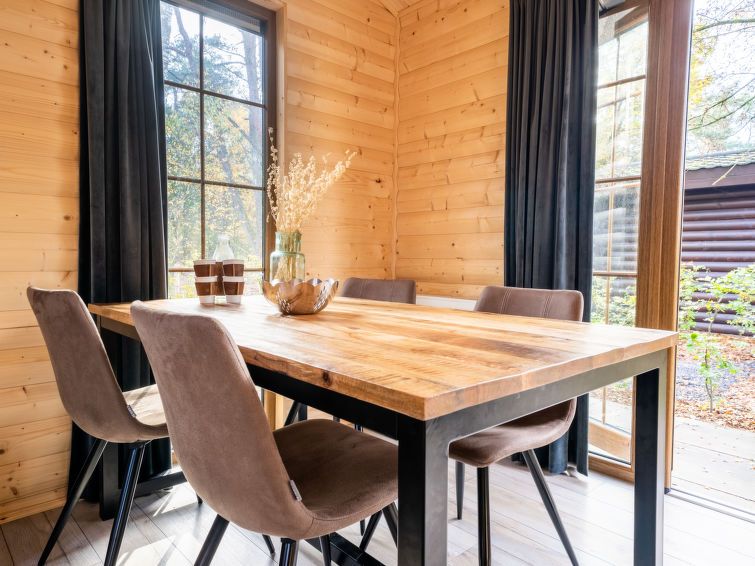 Eetgedeelte met houten tafel in Vakantiehuis Boekhorst 5, Otterlo, Veluwe, omringd door grote ramen en natuurlijk licht.