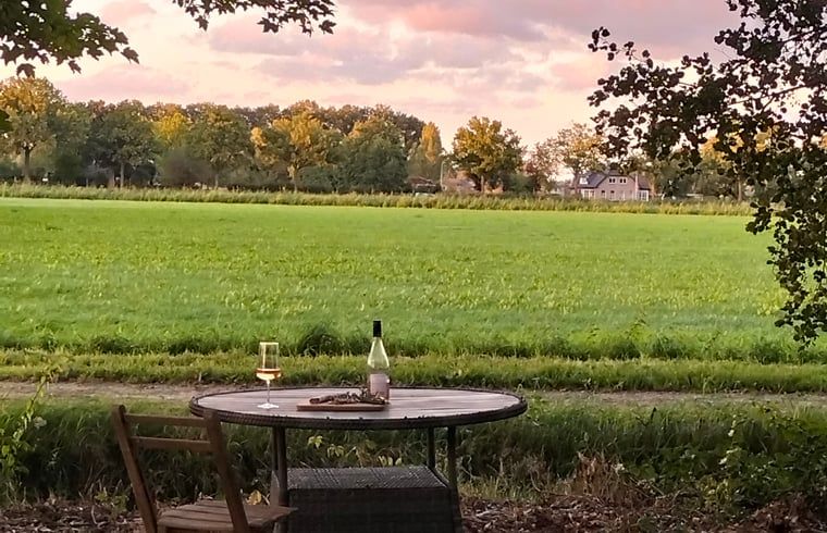 Prachtig uitzicht vanuit Vakantiehuis in Epe, Veluwe, Gelderland op groene velden en een kleurrijke zonsondergang.