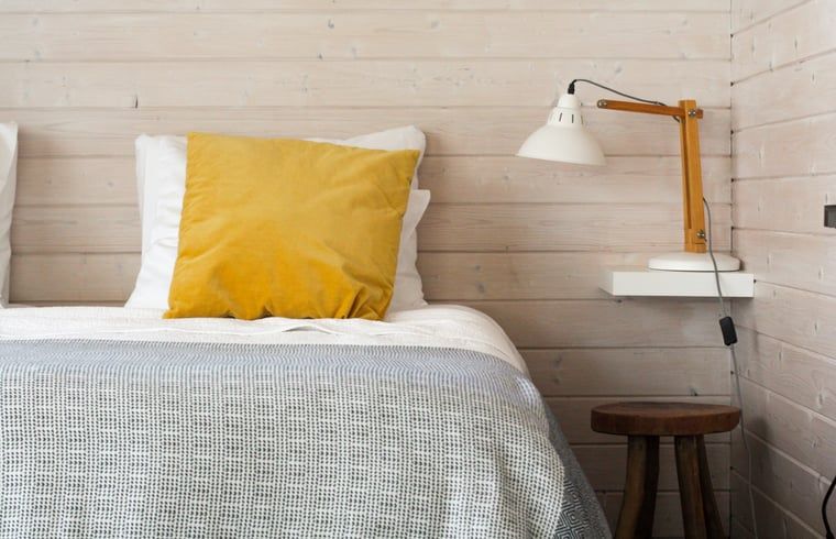 Gemuetliches Schlafzimmer im Ferienhaus in Epe, Veluwe. Bequemes Bett mit hoelzernem Wanddekor und stimmungsvoller Beleuchtung in Gelderland.