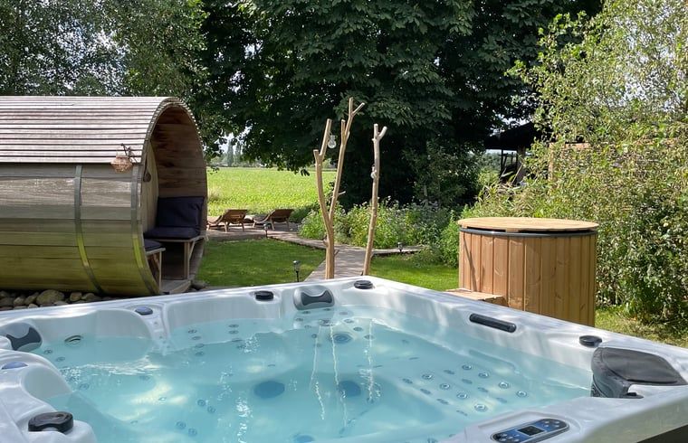 Entspannen Sie sich im Whirlpool des Ferienhauses in Scherpenzeel, Gelderland, mit Blick auf die gruene Veluwe-Landschaft.