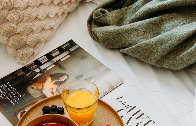 Relaxed breakfast at Holiday Home in Nunspeet, Veluwe, with fresh juice and a magazine in bed.