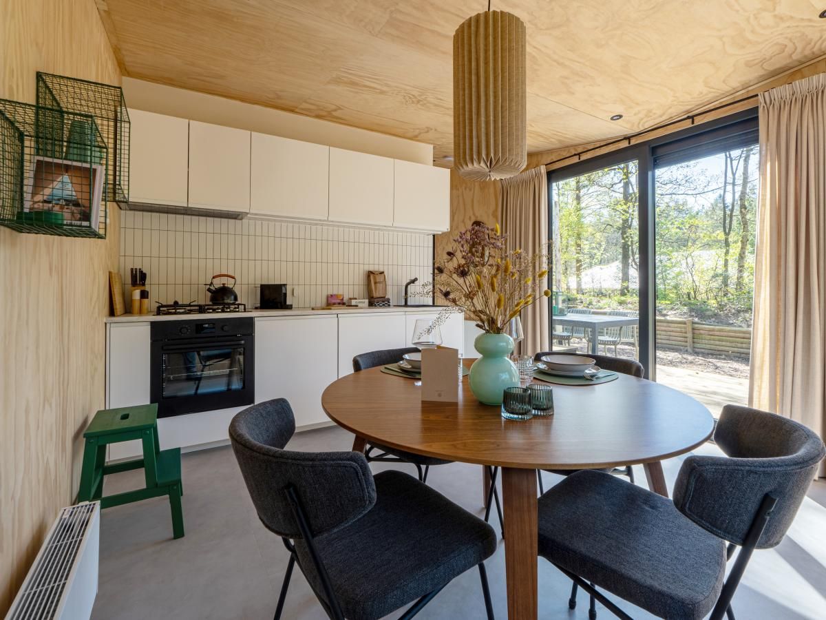 Moderne keuken en eetruimte in vakantiehuis Mos, Nunspeet, Veluwe. Geniet van natuurlijke lichtinval en uitzicht op de bosrijke omgeving.