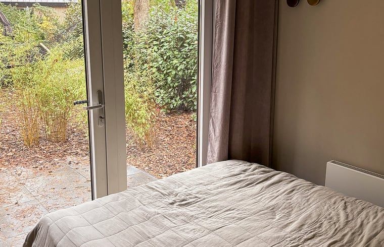 Blick aus dem Schlafzimmer im Ferienhaus in Nunspeet, Veluwe, Gelderland, mit ruhigem Garten und natuerlicher Umgebung fuer ultimative Entspannung.