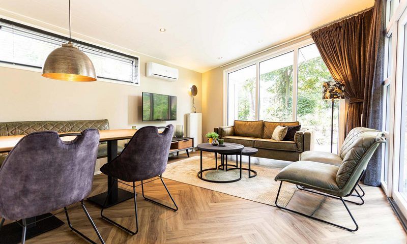 Geraeumiges Wohnzimmer im Silva 4 Personen Wellness Ferienhaus, Lunteren, Veluwe, mit bequemen Moebeln und viel natuerlichem Licht.