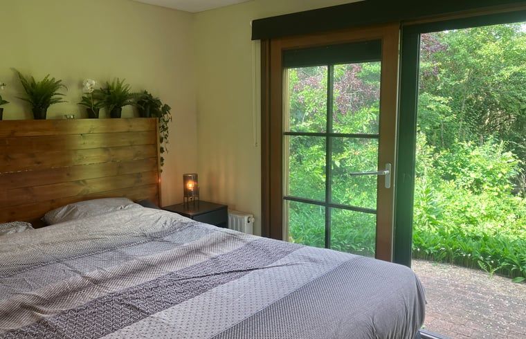 Spacious bedroom in Cottage in Lunteren, Veluwe vacation home, with garden view.