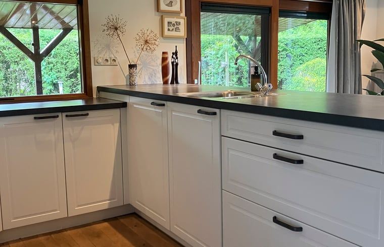 Kitchen in Cottage in Lunteren, Veluwe, with white cabinets and wooden details.