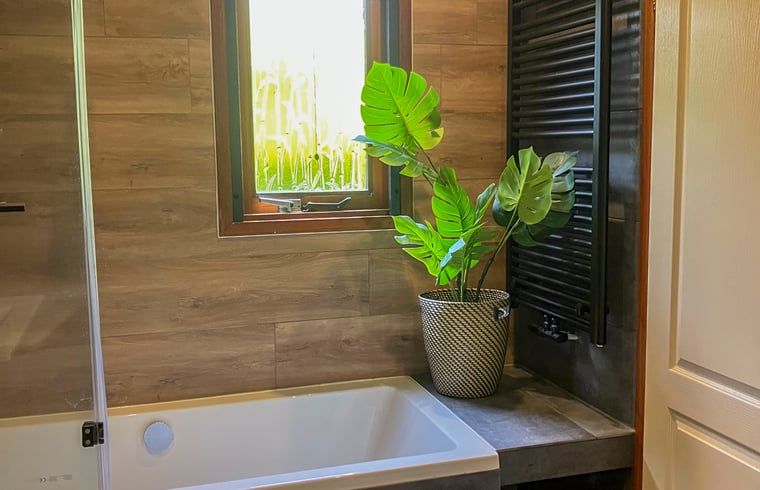 Bathroom in Cottage in Lunteren, Veluwe, with bathtub and green plants for a natural atmosphere.