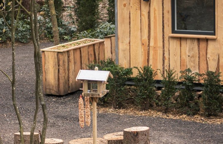 Charmant vakantiehuisje in Uddel, Veluwe, met een gezellige veranda en groene omgeving.