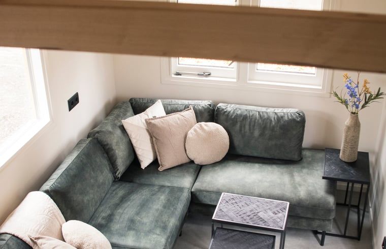 Gezellige zithoek in vakantiehuisje in Uddel, Veluwe, met uitzicht op het groene landschap.