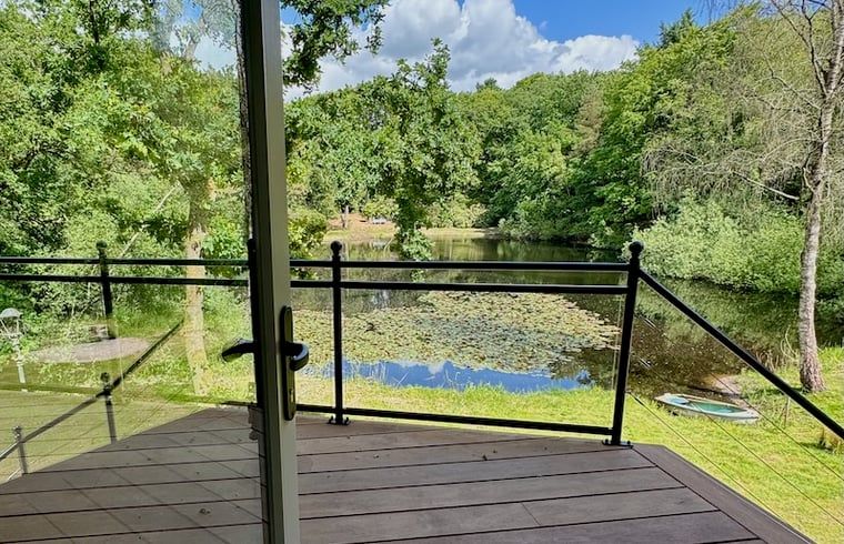 Terrasse des Ferienhauses in Hattem mit schoener Aussicht auf Teich und Wald in Veluwe, Gelderland.