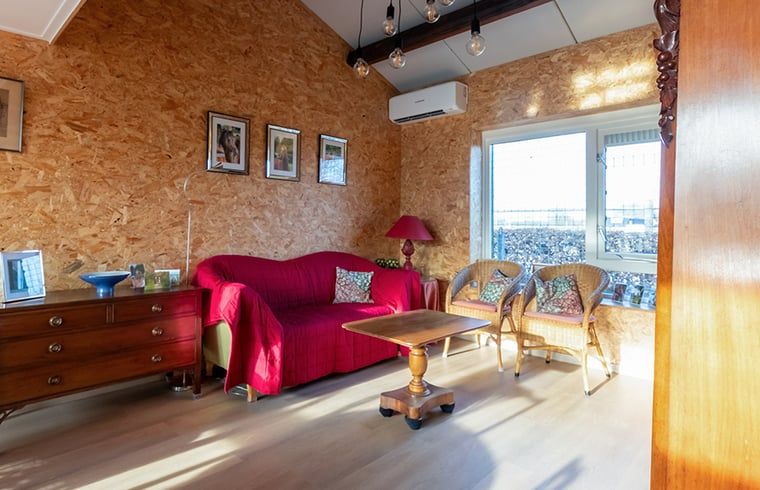 Gemuetliches Wohnzimmer des Ferienhauses in Wapenveld, Veluwe, mit bequemer Sitzecke und viel Tageslicht.