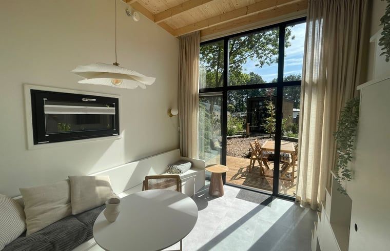 Bright living room with large windows in Holiday home in Lieren.