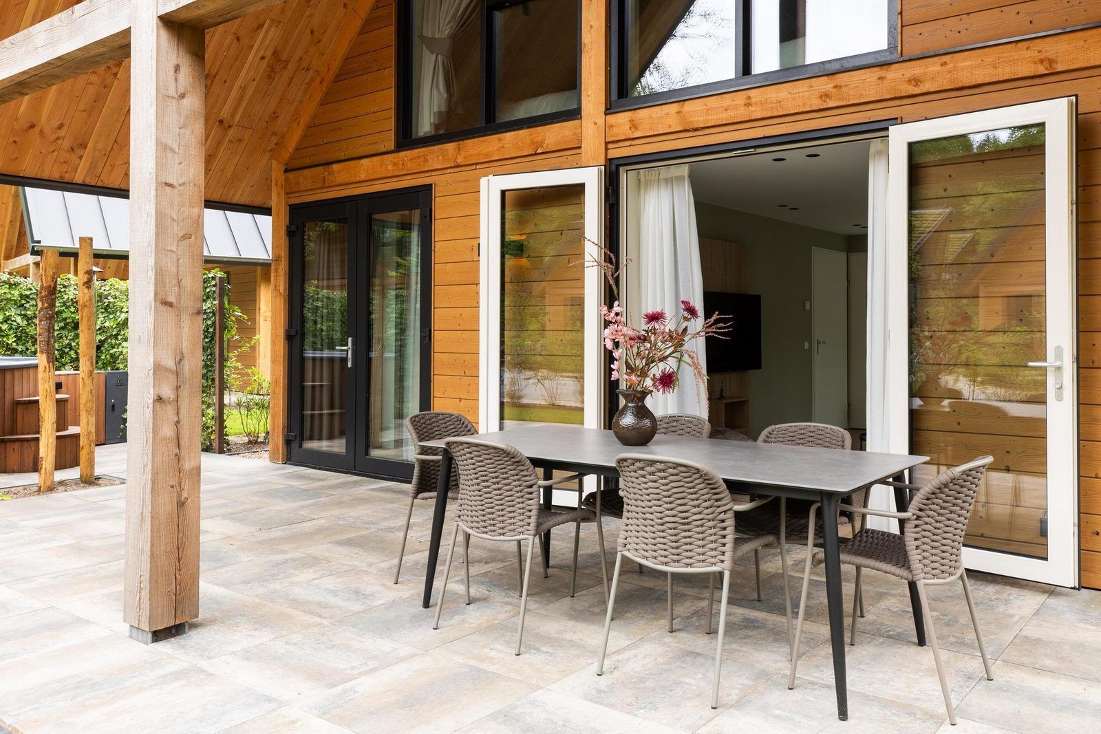 Offene Terrasse mit Esstisch in Bos Villa mit Whirlpool & Sauna in Wekerom, Veluwe, Gelderland. Ferienhaus fuer sechs Personen.