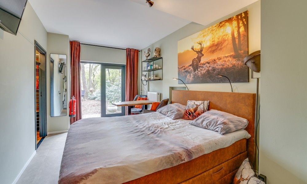 Attraktives Schlafzimmer des Studios REE in Wekerom, Veluwe, Gelderland mit Blick auf ein bewaldetes Gebiet.