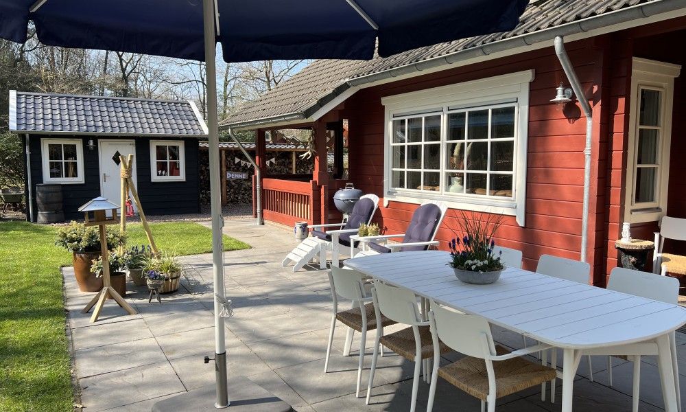 Sunny terrace with dining table at Boshuis Denne, vacation home in Bennekom, Veluwe, Gelderland for outdoor meals.