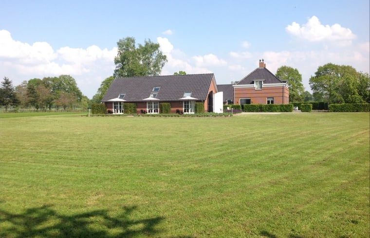 Vakantiehuisje in Eerbeek op de Veluwe, Gelderland, omgeven door een uitgestrekt groen veld en rustieke charme.