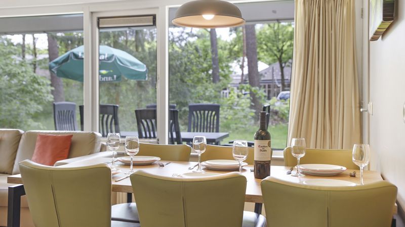 Eethoek in Rabbit Hill bungalow met uitzicht op terras en groen, Veluwe.