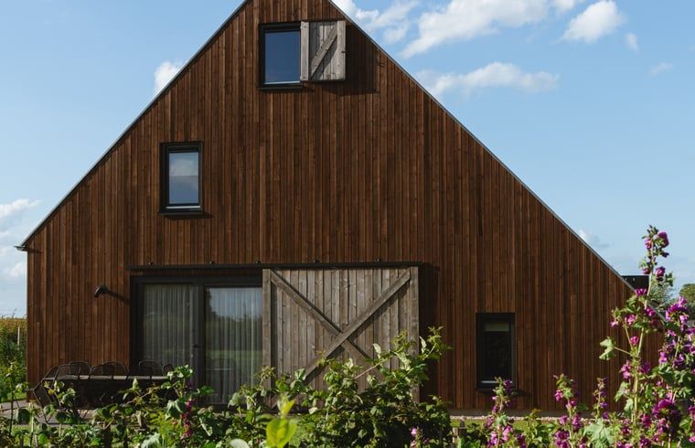 Huisje in Veessen, een rustiek vakantiehuis op de Veluwe in Gelderland, met houten gevel en bloementuin.