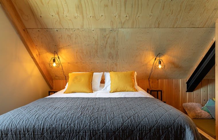 Knusse slaapkamer met houten afwerking in Huisje in Veessen, Veluwe, voor een ontspannen verblijf.