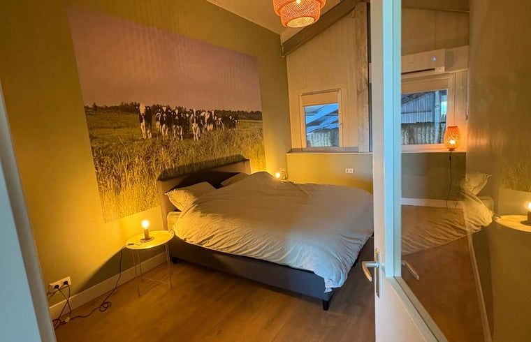 Attractive bedroom in Holiday cottage in Schildwolde, northeastern Groningen, with comfortable bed and country mural.