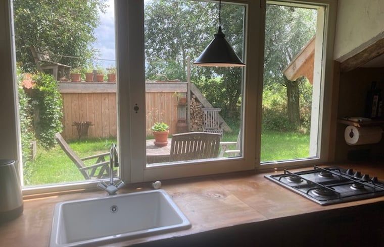 Keuken met uitzicht op tuin in Vakantiehuis in Overschild, Noordoost Groningen.