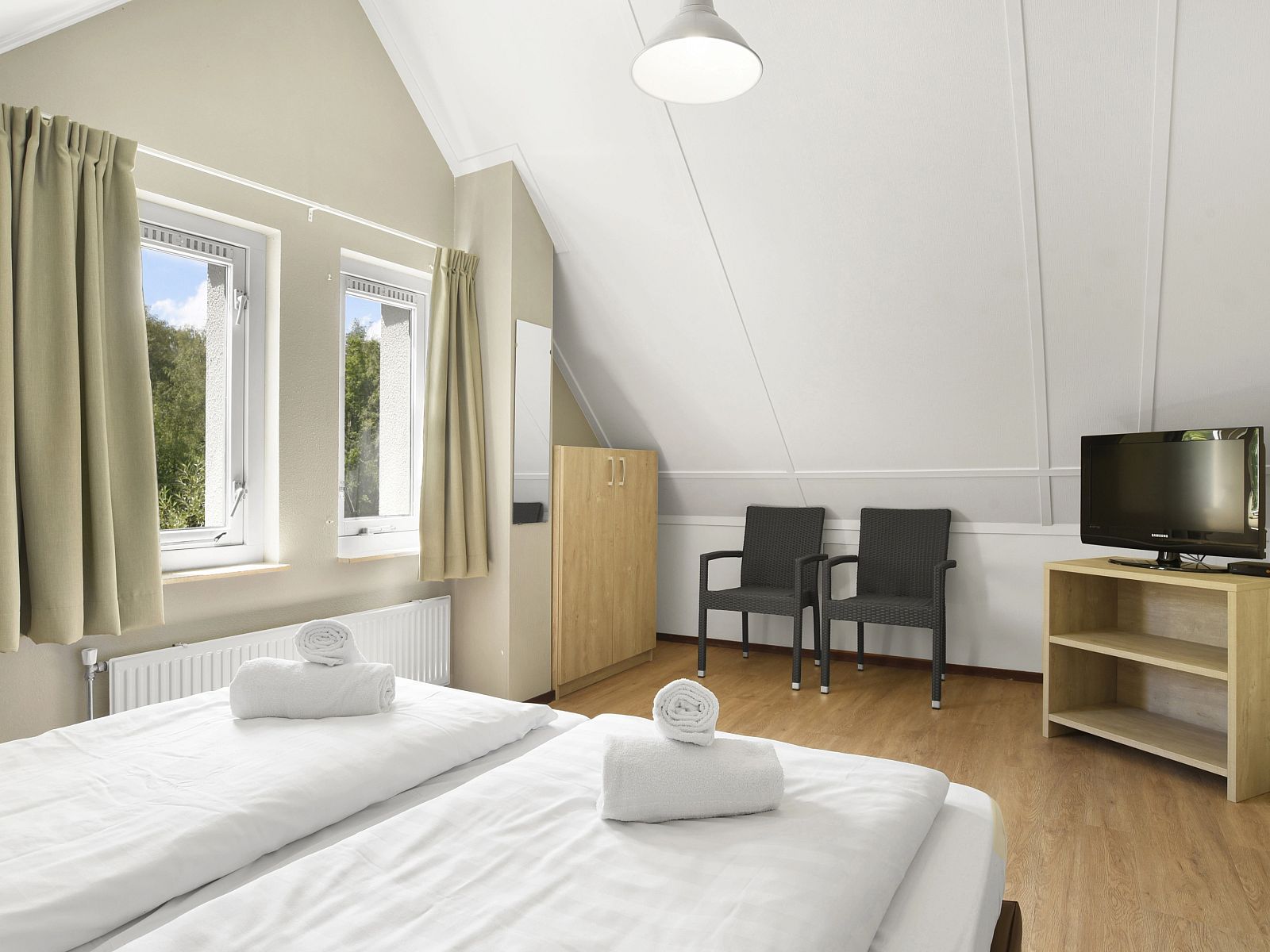Bedroom with sitting area and TV in Natuurdorp Suyderoogh bungalow, Lauwersoog, Groningen.