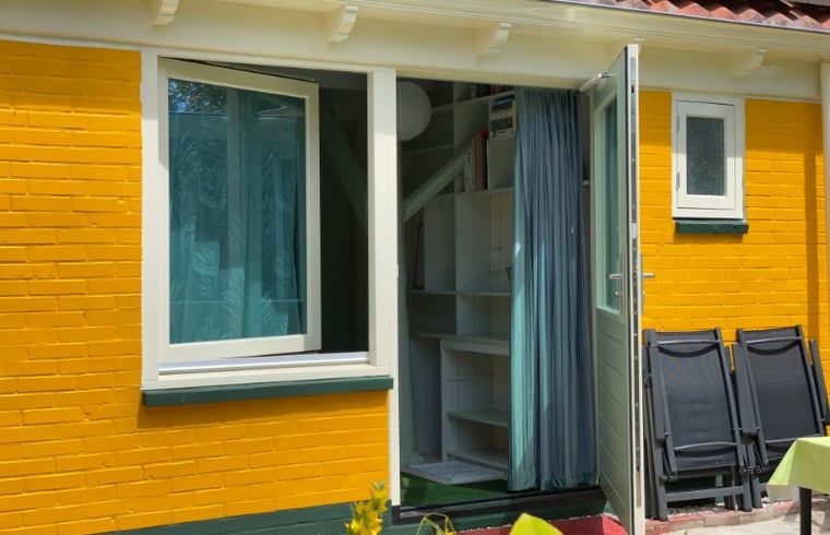 Buitenkant van Vakantiehuisje in Molenrij, met levendige gele muren in Noordwest Groningen.