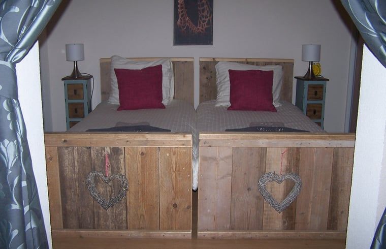 Attraktives Schlafzimmer im Huisje in Ter Apel, einem Ferienhaus im Suedosten von Groningen mit rustikalen Holzbetten und warmen Akzenten.