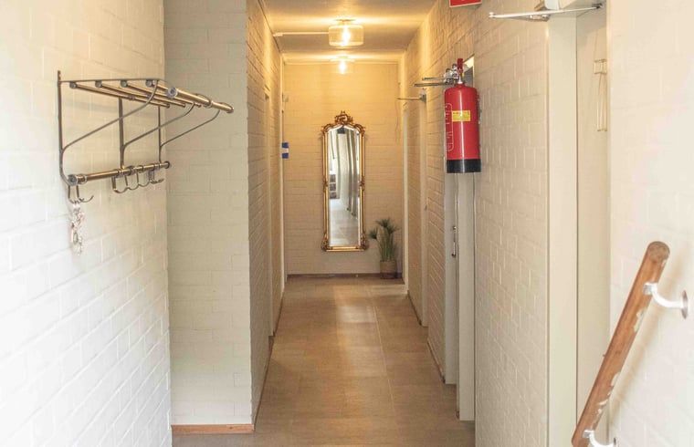 Langer Flur mit Spiegel in Cottage in Bourtange Ferienhaus, bietet Zugang zu mehreren Zimmern in Groningen.