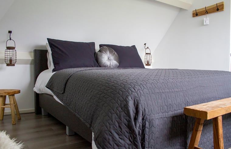 Slaapkamer met houten accenten in Huisje in Marum, vakantiehuis in Zuidwest Groningen.