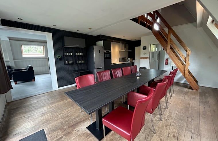 Spacious dining room in Holiday Home in Stramproy, Central Limburg, with modern kitchen and long dining table, ideal for family gatherings.