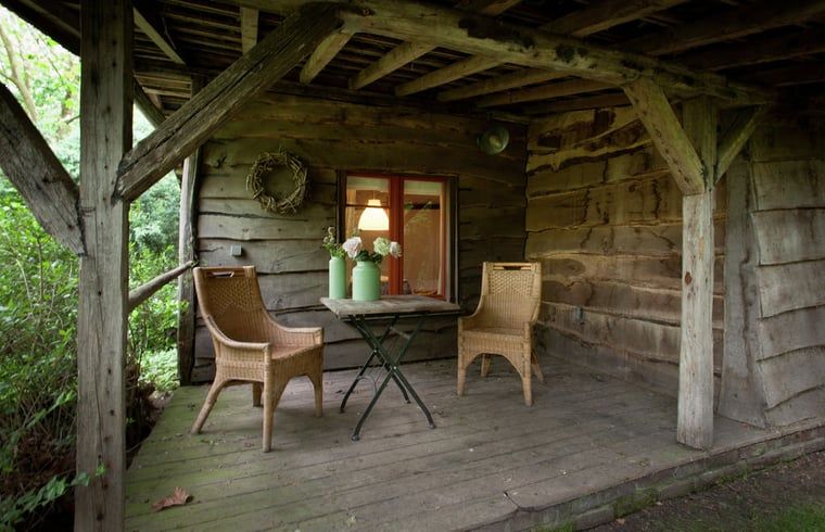Geniet van de rust op de houten veranda van Huisje in Leudal, een sfeervol vakantiehuis in het groene Leudal, Midden Limburg.