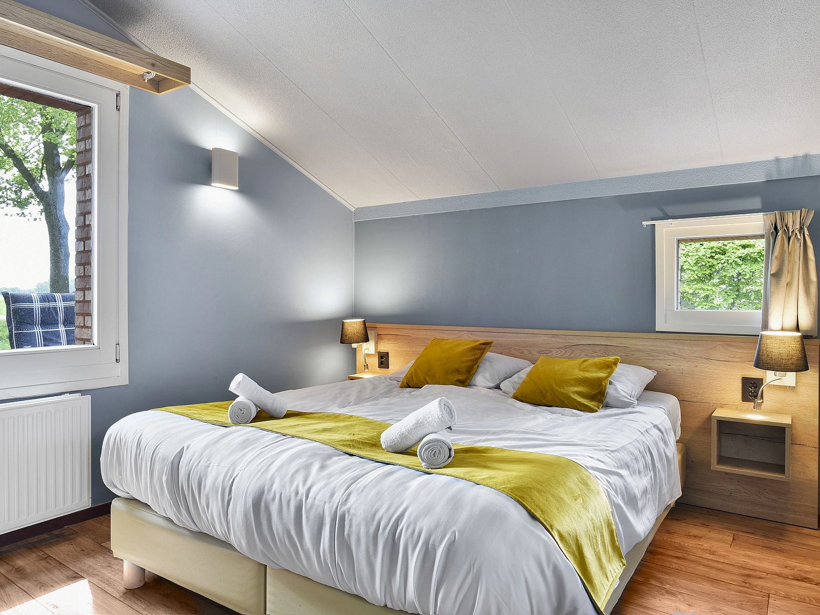 Slaapkamer met tv en kast in Landgoed Aerwinkel 4-persoons bungalow 4BL, Posterholt, Limburg, met uitzicht op de natuur.