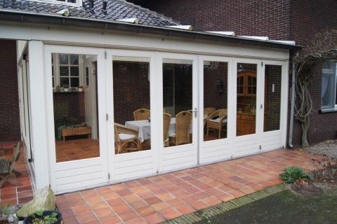 Sonnige Veranda der Ferienvilla Hubertushof in Horst, Nord-Limburg, mit Glastren und Blick auf den Garten.