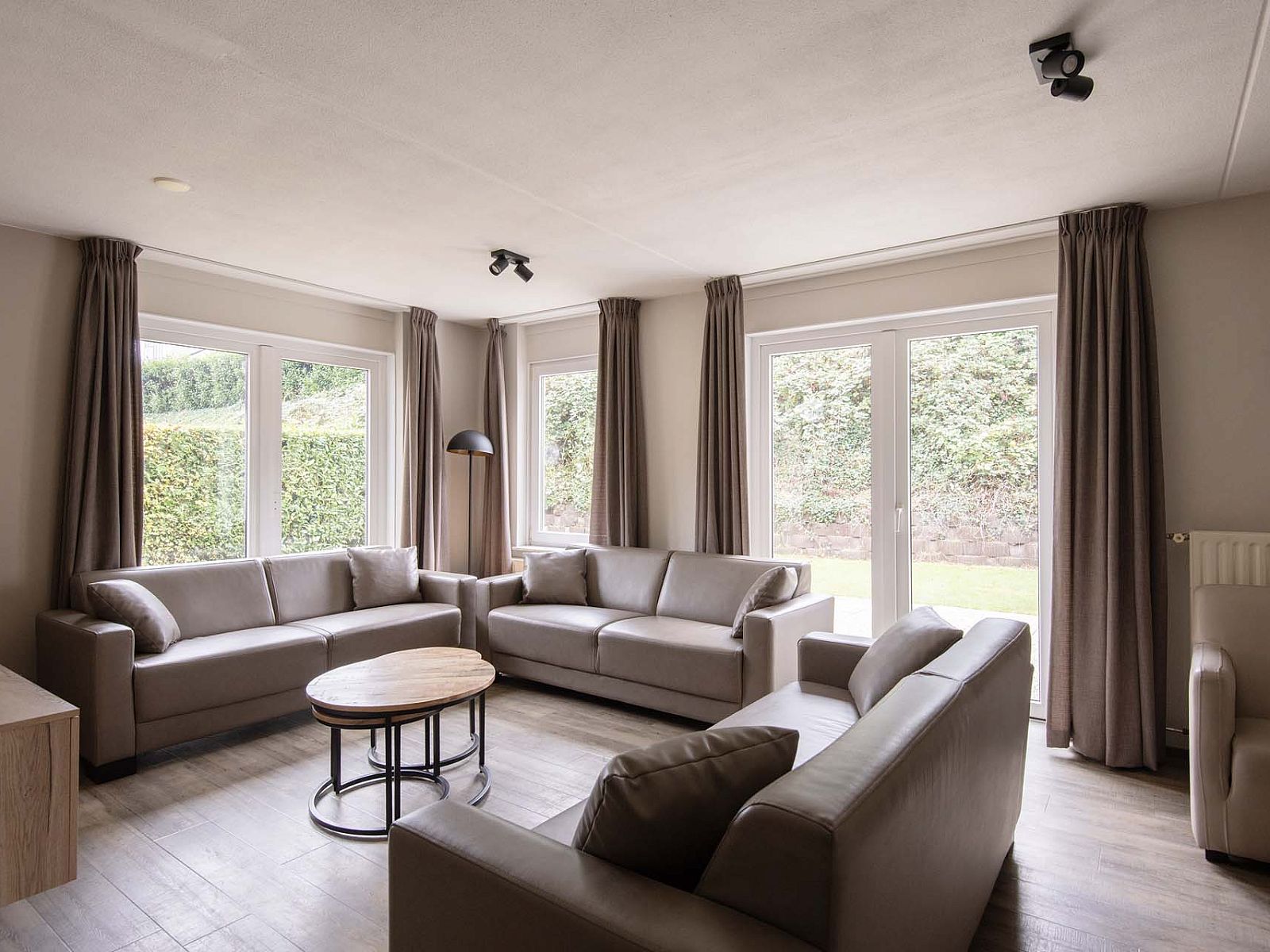 Gezellige woonkamer in de Vrijstaande woning in Arcen, Noord Limburg, met comfortabele banken en uitzicht op de groene tuin.