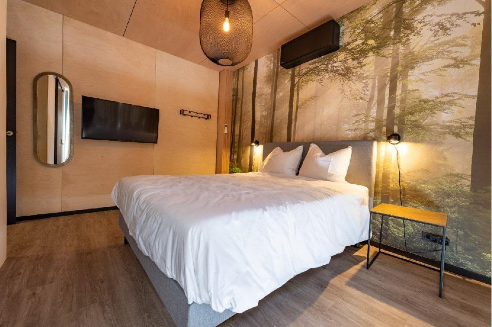 Luxurioeses Schlafzimmer in Bos Villa DeLuxe XL in Maasbree, Nord-Limburg, mit bequemem Bett und stimmungsvoller Waldwanddekoration.