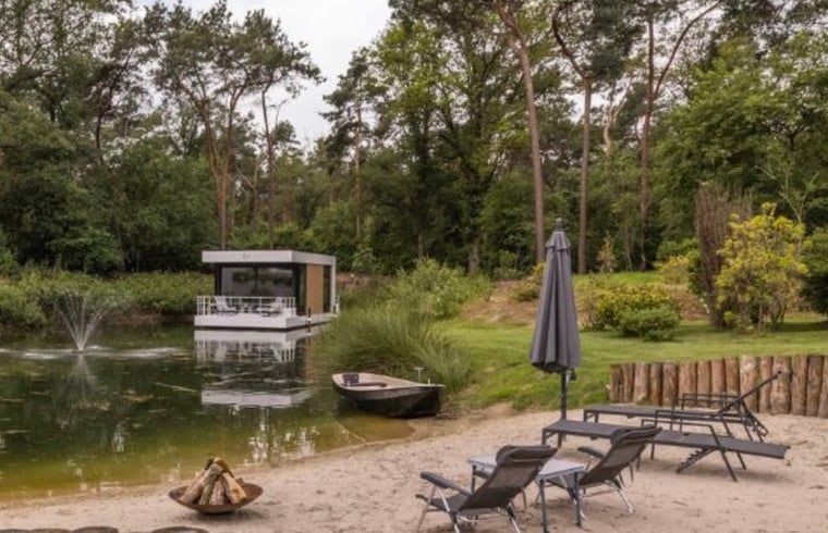 Rustikaler Strand in der Naehe des Ferienhauses in Merselo, Nord-Limburg, mit Liegestuehlen und einem Boot.