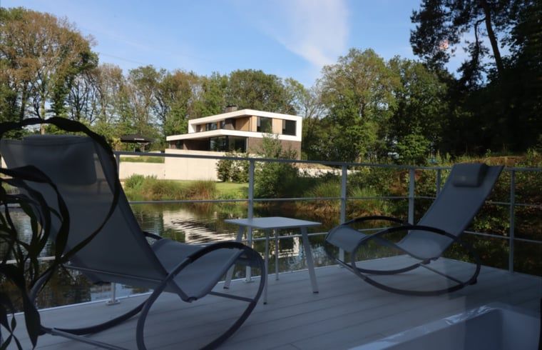 Veranda des Ferienhauses in Merselo, Nord-Limburg, mit bequemen Stuehlen und Blick auf den Teich.