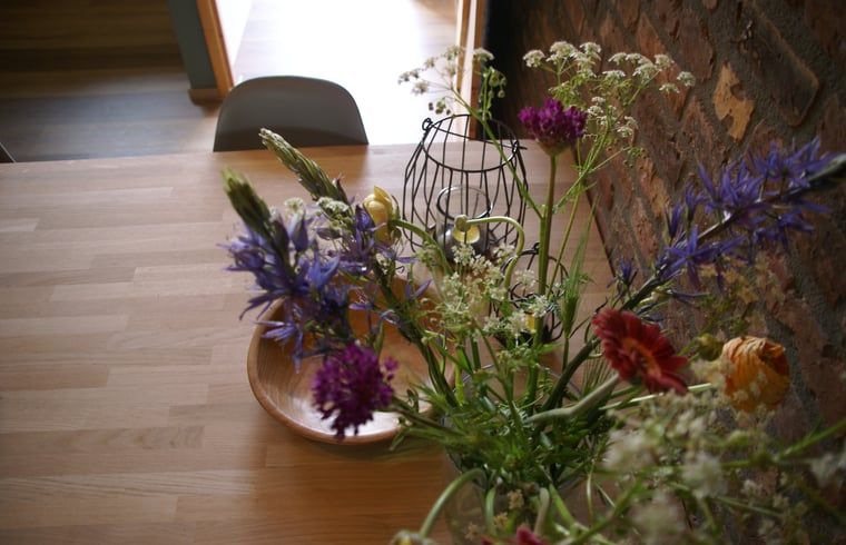Verse bloemen op tafel in Vakantiehuisje in Grashoek, Noord Limburg. Gezellige sfeer met kleurrijke bloemen.