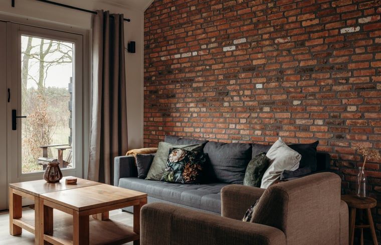 Gezellige woonkamer in Vakantiehuisje in Grashoek, Noord Limburg. Comfortabele zithoek met houten meubels.
