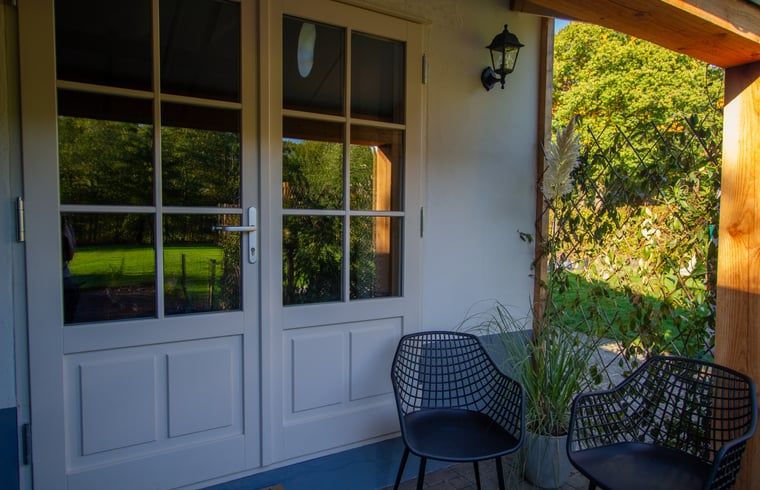 Gezellige veranda van Vakantiehuis in Griendtsveen, Noord Limburg, met uitzicht op groene natuur en comfortabele zitjes.