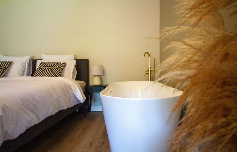Luxe slaapkamer met vrijstaand bad in Vakantiehuis in Griendtsveen, Noord Limburg. Geniet van comfort en rust in deze sfeervolle vakantiewoning.