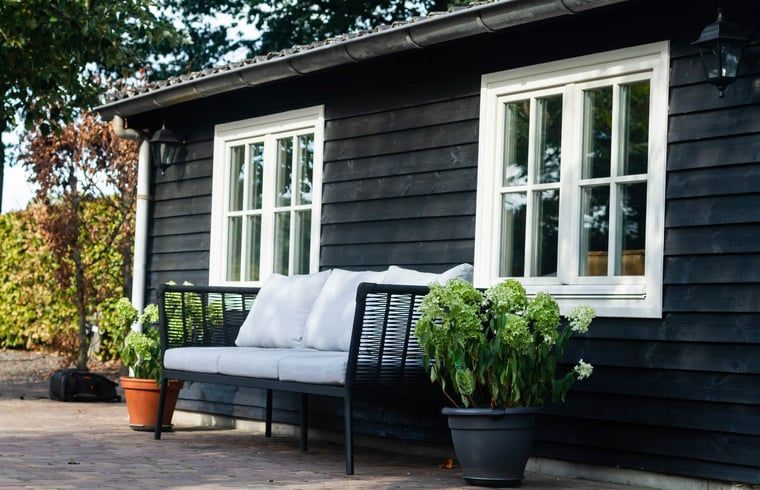 Geniet van de rust op de veranda van Vakantiehuisje in Griendtsveen, Noord Limburg, met comfortabele zitplek in de groene omgeving.