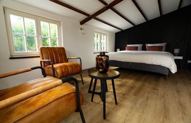 Gezellige slaapkamer in Vakantiehuisje in Griendtsveen, Noord Limburg met houten balken en comfortabele stoelen voor een ontspannen verblijf.