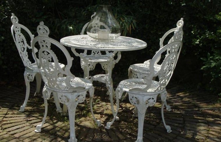 Charming terrace with wrought iron table and chairs at Cottage in Valkenburg, vacation home in South Limburg.
